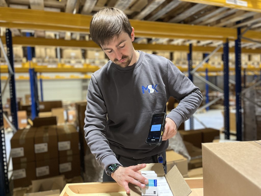 Healthcare logistics professional carefully scanning medicine packages for serial number verification.